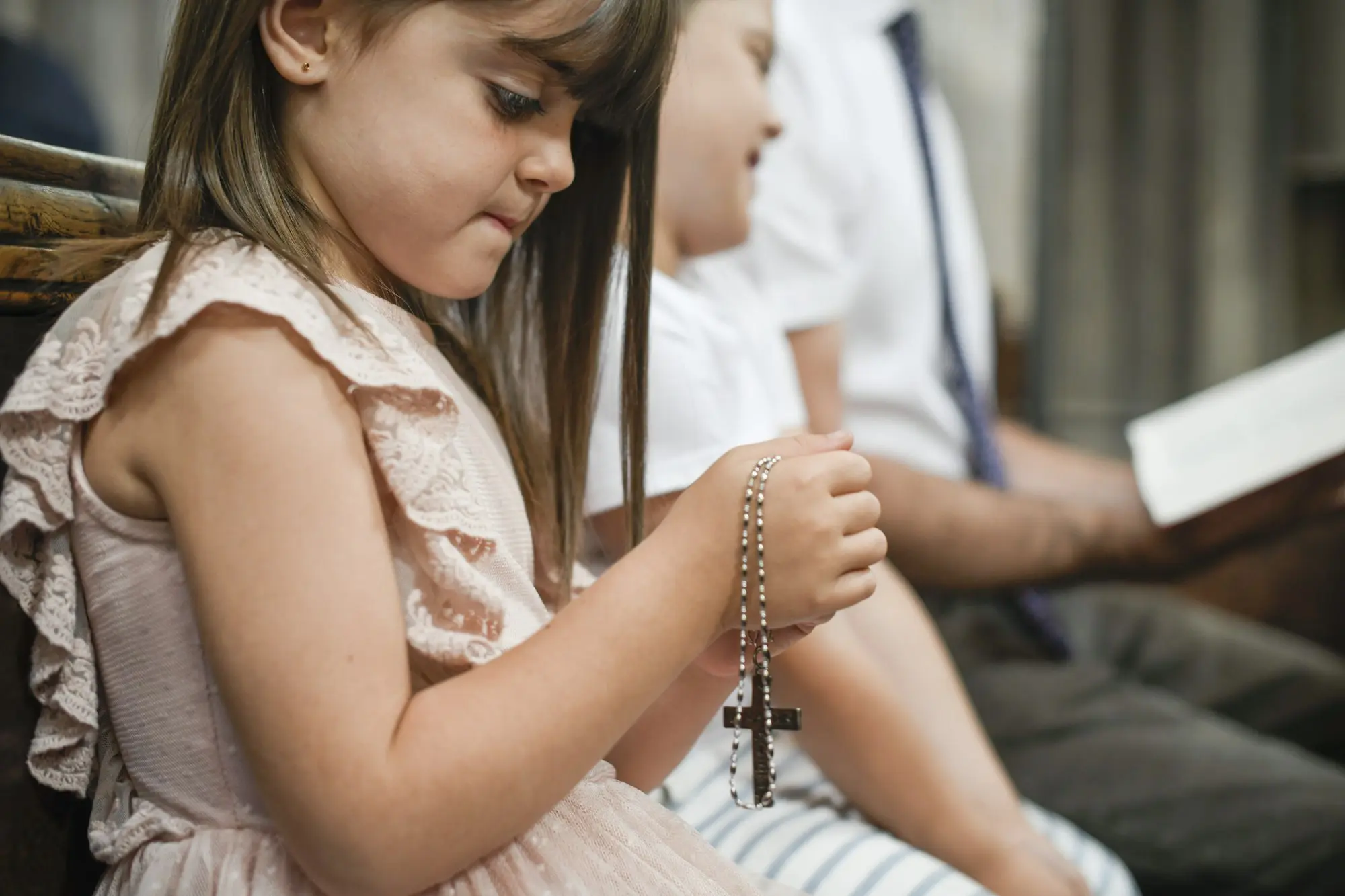Little catholic girl praying with a rosary in her hands